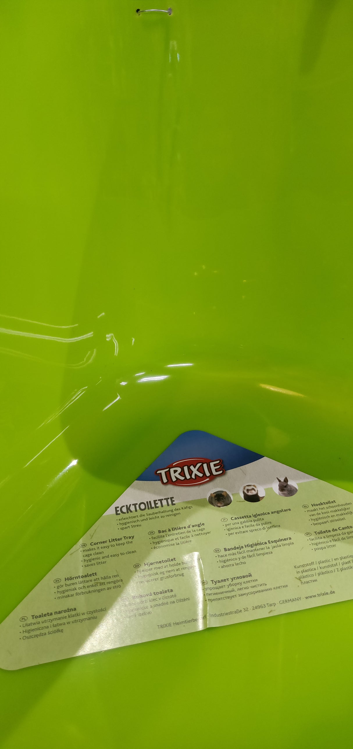 En grøn plastikbeholder med en etiket på egnet til Hjørnetoilet til kaniner, marsvin, fritter o.l. (gnavere) af Trixie.