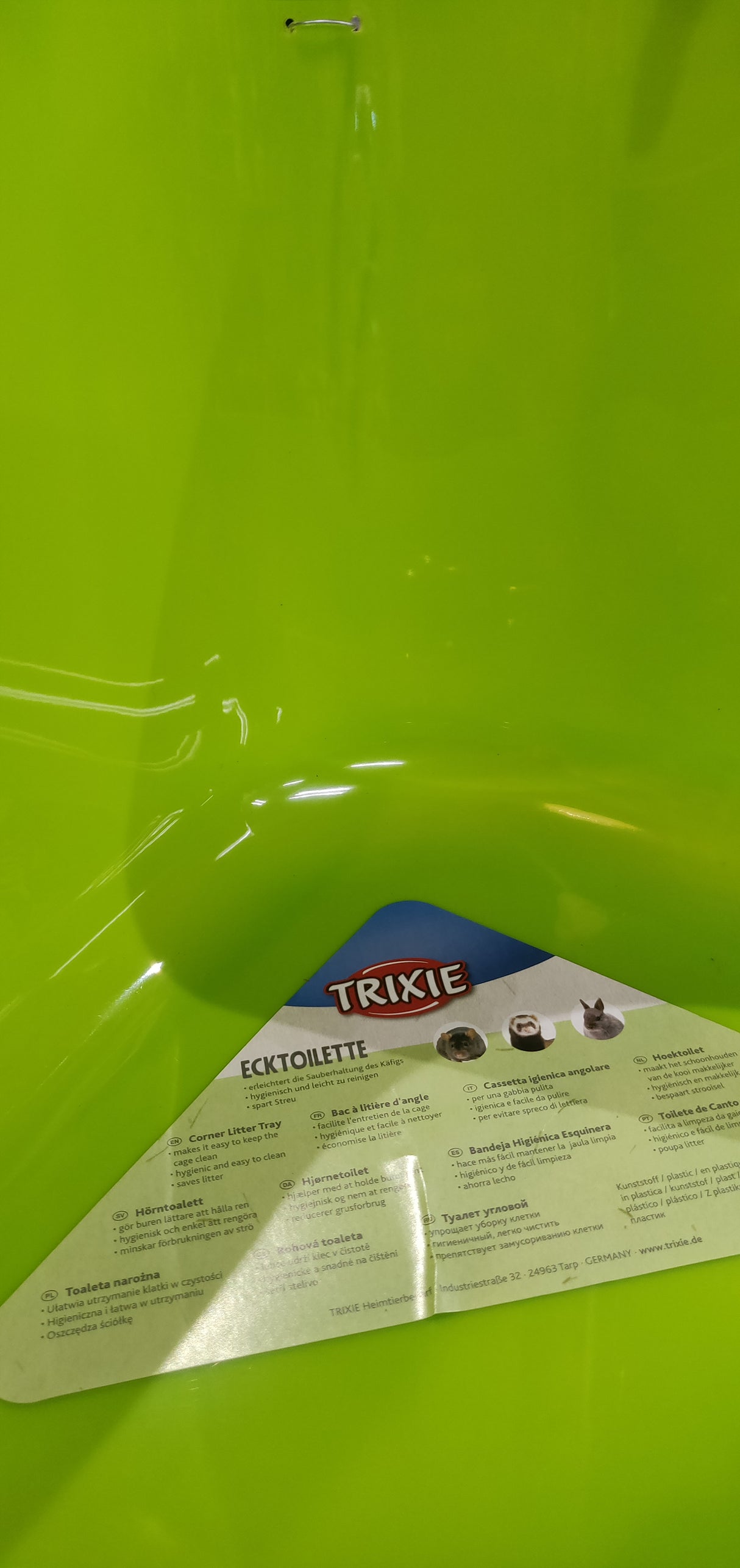 En grøn plastikbeholder med en etiket på egnet til Hjørnetoilet til kaniner, marsvin, fritter o.l. (gnavere) af Trixie.