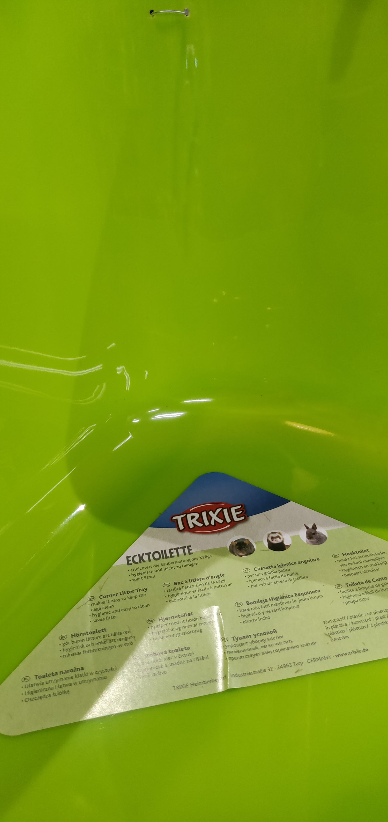 En grøn plastikbeholder med en etiket på egnet til Hjørnetoilet til kaniner, marsvin, fritter o.l. (gnavere) af Trixie.
