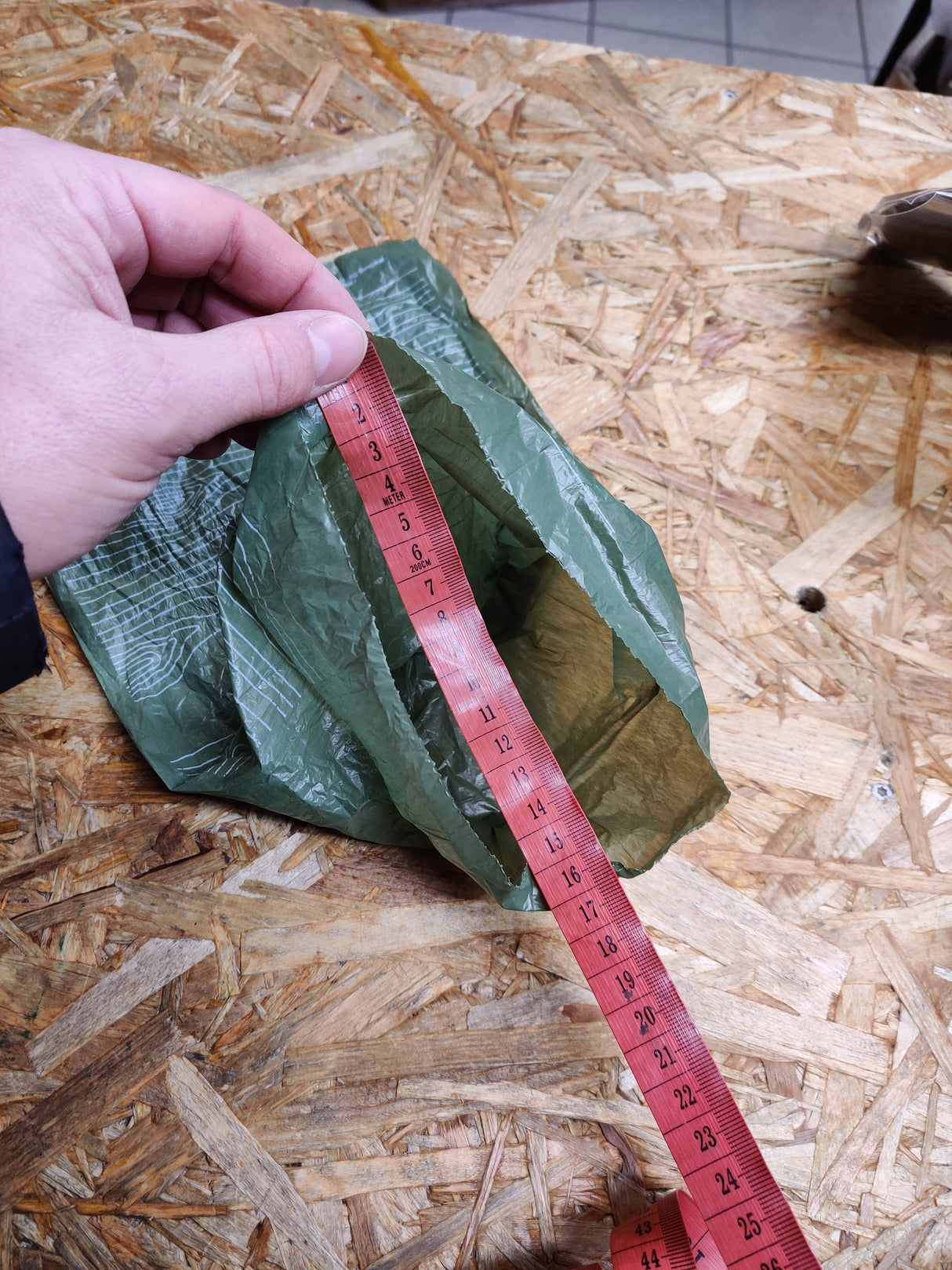 En person måler en pose biologisk nedbrydeligt Høm Høm hundeposer, miljøvenlige fra PoopyGo 300 poser på et træbord.