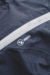 Nærbillede af en sort jakke med en hvid stribe. Hurtta Drizzle-regnjakken.