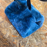 En blå pelspose, også kendt som "Hamsterhule i lækkert plys" eller "Trixie", der sidder på et trægulv.