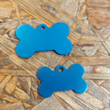 To "Hundetegn, lyseblå formet som kødben" med stik på træoverflade fra "Os med kæledyr".