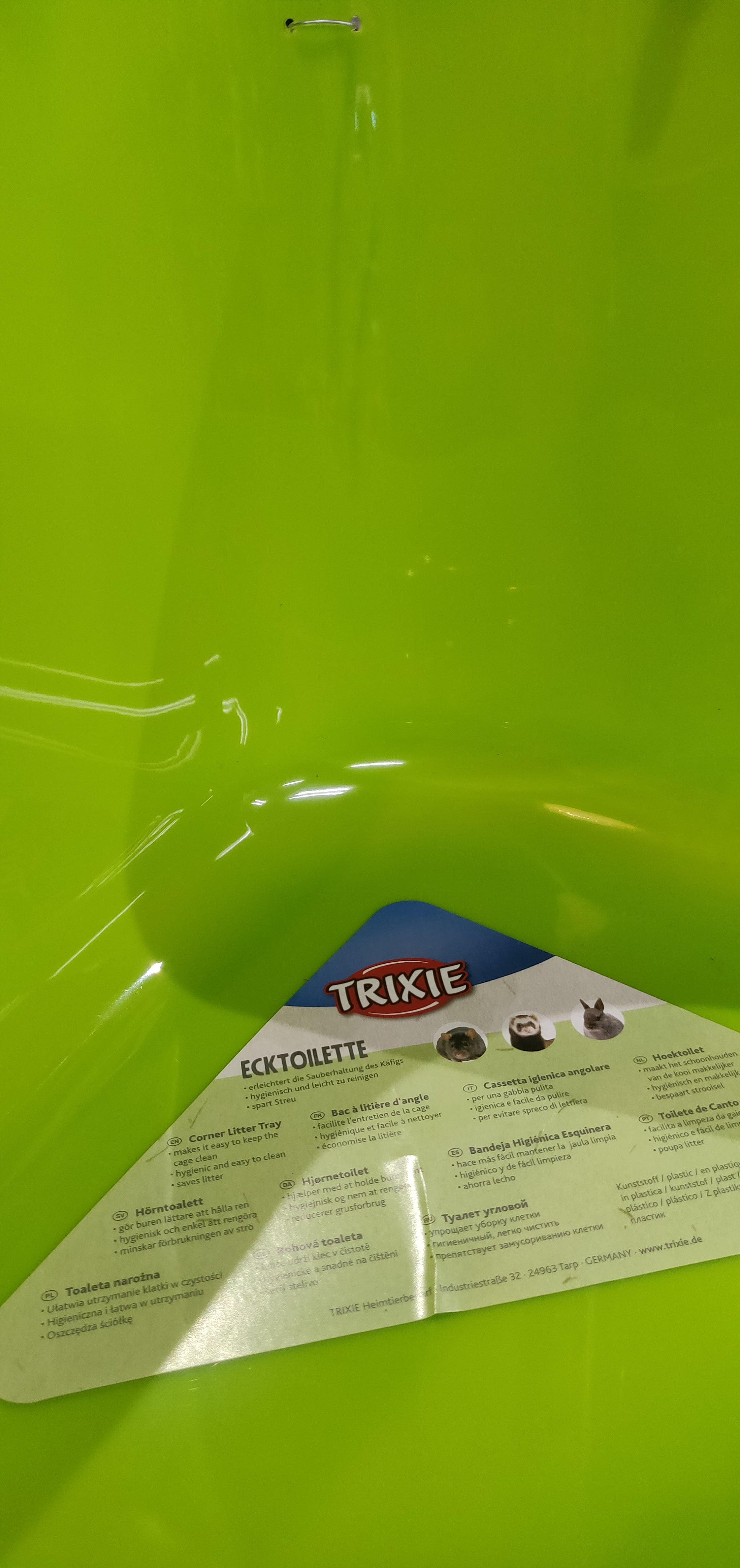 En grøn plastikbeholder med en etiket på egnet til Hjørnetoilet til kaniner, marsvin, fritter o.l. (gnavere) af Trixie.
