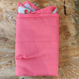 En pink Hængekøje til rotter og marsvin taske, fremstillet af Trixie, der sidder oven på et træbord, sammen med en guldhamster.