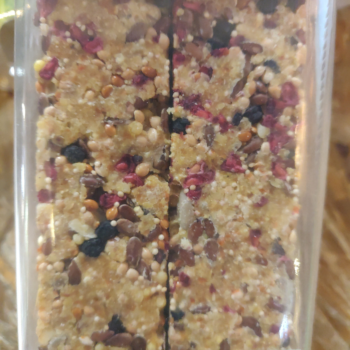 To stænger Fugle kracker med frugt, fra JR Farm 150g granola i en plastikbeholder.