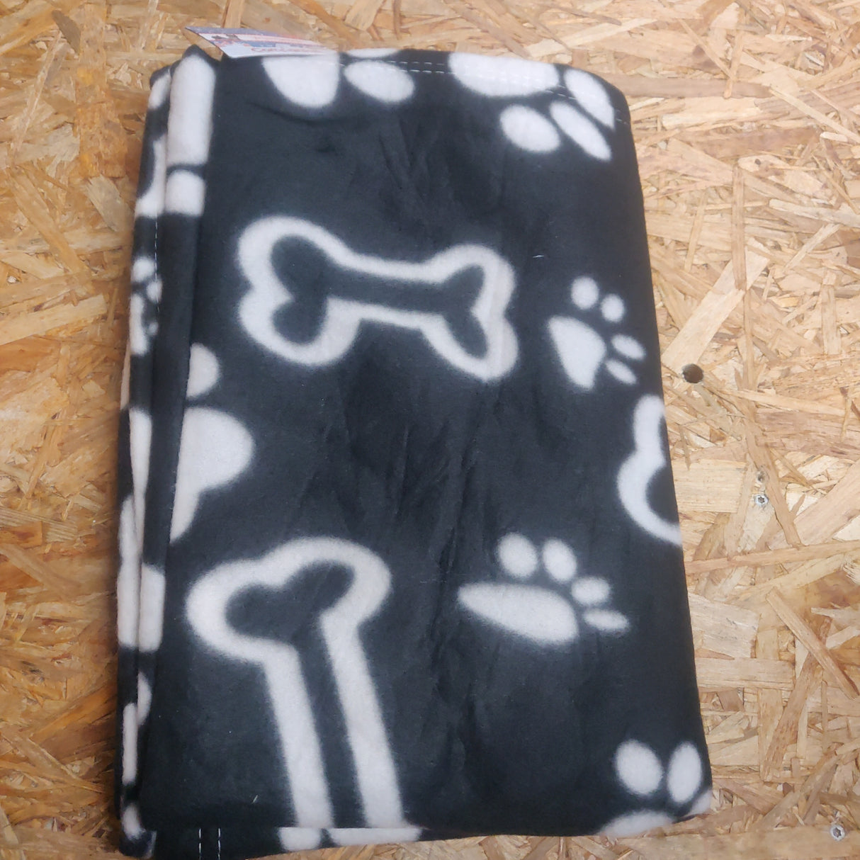 En sort/hvid Trixie Fleecetæppe med hundepoteprint på, fås i Jul/2 størrelser.
