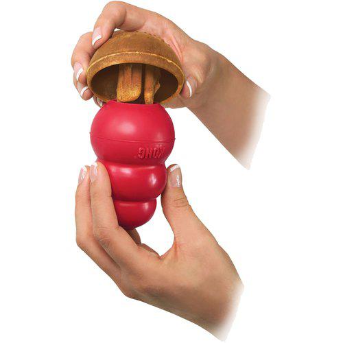 En person, der holder en Godbid med peanutbutter, til Kong Original Kong - Ekstrem bold i hænderne, der nyder den legende interaktion.