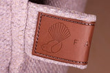 Et nærbillede af en brun læder Hundeseng Fantail Snooze Epic Grey en lækker grå seng med høj kant taske med en fugl på.