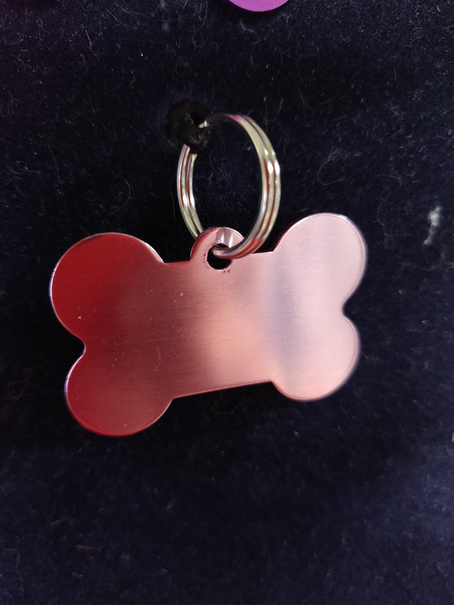 Et Hundetegn, lyserød formet som kødben tag med gravering på sort baggrund fra Os med kæledyr.