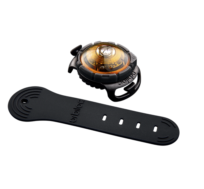 Et Orbiloc sort og orange ur med et kraftigt lys på en sort baggrund.