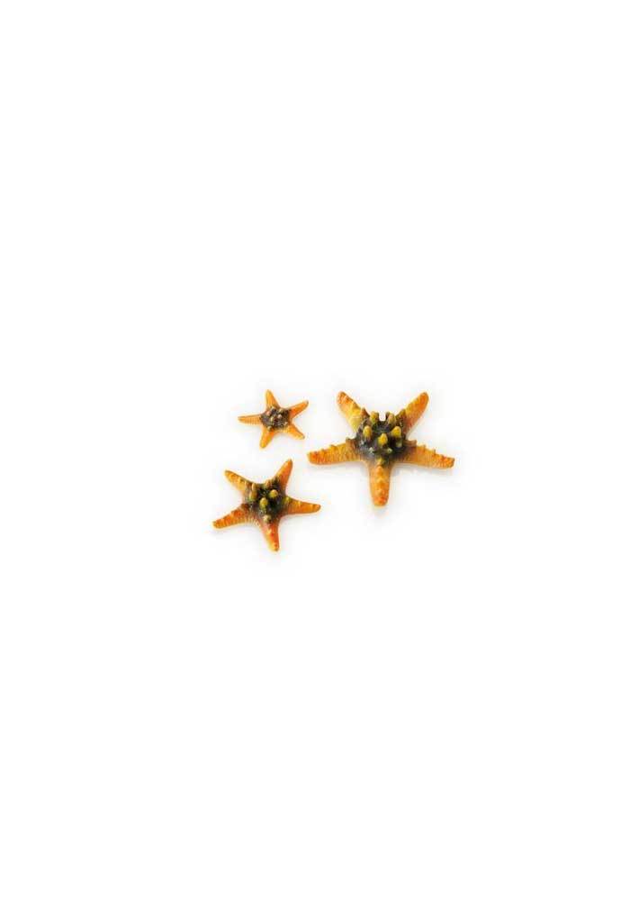 Tre biOrb orange søstjerner på en hvid overflade i et akvarium.