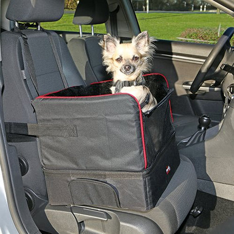 En lille hund fastgjort med en Trixie sikkerhedssele på bagsædet af en bil.