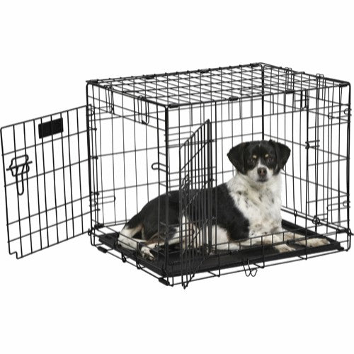 En hund, der ligger i en Trixie Hundebur, sort transportbur.