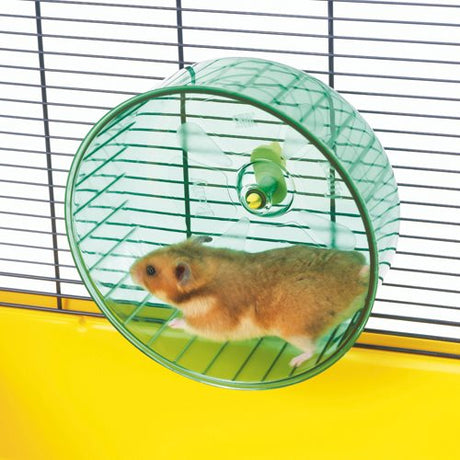 En hamster sidder i et Savic grønt og gult bur med Løbehjul til hamsterburer fra Savic.