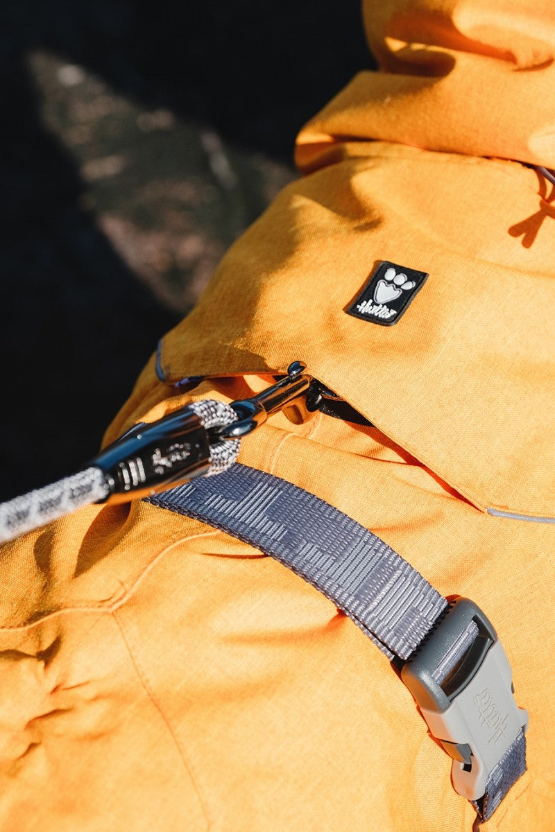 En person iført Hurtta - Expedition Parka Støvet orange (Buckthorn) jakke i koldt vejr, med et reb fastgjort til.