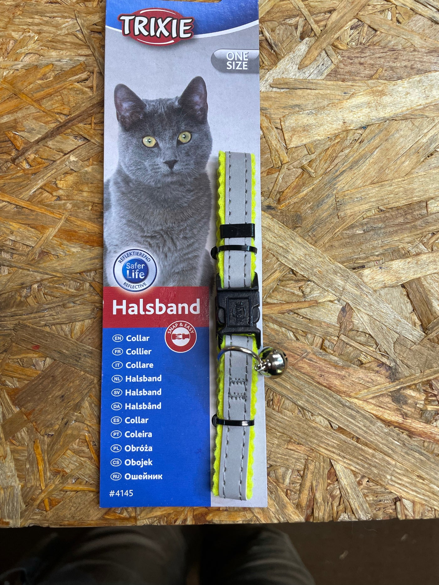 En kat har et Trixie Kattehalsbånd m/ reflex og klokke på et bord.